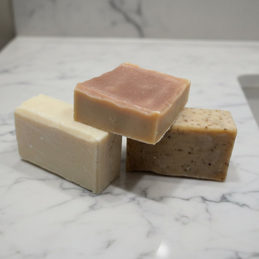 Three bars of soap stacked on a textured surface with a dark background